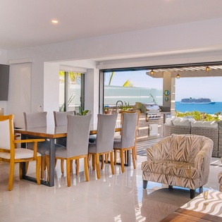 Step into your bright, open-plan living space where floor-to-ceiling windows frame stunning ocean views and tropical breezes flow through.