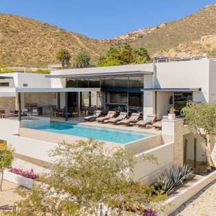 Modern villa nestled in desert hills with sparkling pool and mountain backdrop.