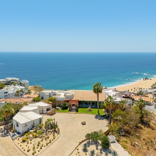 Stunning aerial perspective of a coastal property with pristine beaches and turquoise waters stretching to the horizon.