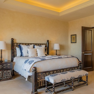 Sink into luxury in your elegant master bedroom, where ornate furnishings and warm golden lighting create a regal retreat for restful nights.