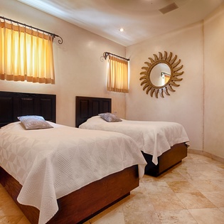 Rest easy in this inviting bedroom with two plush beds, warm sunlight through golden curtains, and modern comforts including a flat-screen TV for your relaxation.