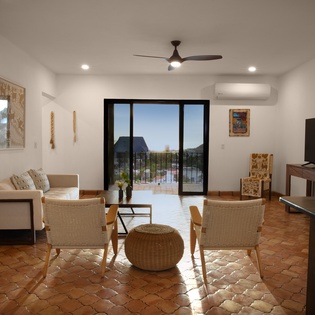 Relax in your bright living space with terracotta floors, modern furnishings, and balcony access to enjoy peaceful views.