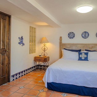 Sink into crisp linens in your serene bedroom, where handcrafted woodwork and colorful tile floors create authentic charm for your restful escape.