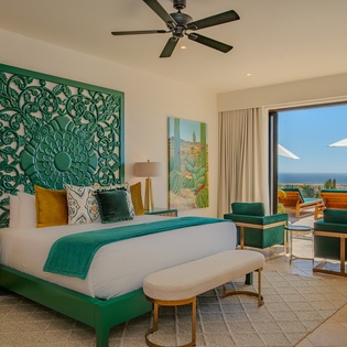Your vibrant bedroom sanctuary features emerald accents and opens to breathtaking ocean views, creating the perfect retreat for relaxation.