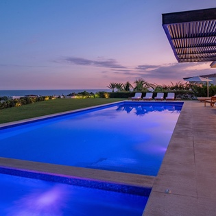 Pool and jacuzzi with ocean view during sunset