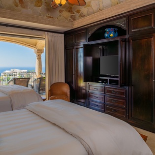 Wake up to stunning ocean views from your luxurious bedroom, where rich wood furnishings and elegant stone details create the perfect retreat.