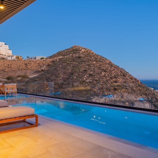 Infinity pool captures breathtaking coastal mountain views in the golden evening light.