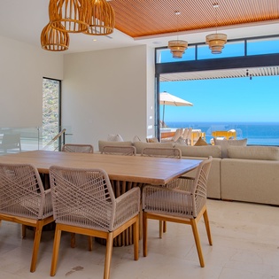 Gather around your elegant dining table while soaking in breathtaking ocean views through floor-to-ceiling windows that frame the endless blue horizon perfectly.