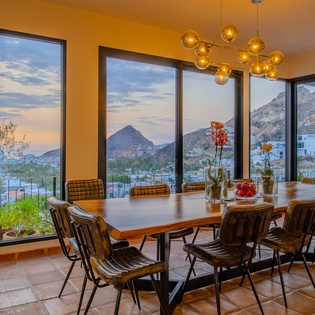 Gather around the dining table with dramatic mountain views through floor-to-ceiling windows. The warm lighting and modern design create the perfect setting for memorable meals together.