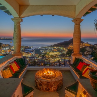 Unwind on your private terrace with stunning sea views, cozy fireplace, and vibrant sunset skies creating the perfect evening retreat.