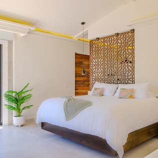 Drift off in this serene bedroom with tropical touches and stunning geometric headboard design for your perfect retreat.