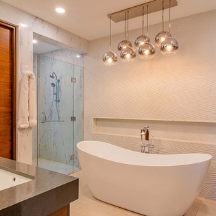 Sink into relaxation in your freestanding soaking tub, where elegant designer lighting and wave-textured walls create a spa-like retreat for unwinding after a day of adventure.