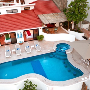 Aerial view of the property showcasing a curved swimming pool with integrated hot tub and outdoor lounging areas.