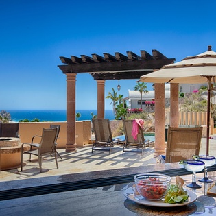 Stunning rooftop terrace features ocean views, shaded lounge seating, and an outdoor bar perfect for enjoying sunset cocktails and fresh salsa overlooking the sparkling sea.