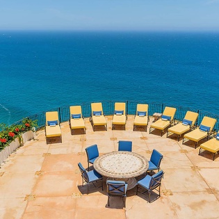 Stunning ocean-view terrace with sun loungers and dining area overlooking the endless blue horizon, perfect for relaxation and scenic dining.