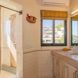 Unwind in your spacious bathroom with dual sinks, natural stone counters, and views of surrounding hills through bamboo-shaded windows.