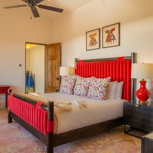 Your vibrant bedroom features a bold red headboard, crisp linens, and colorful artwork that creates a cheerful retreat for restful nights.