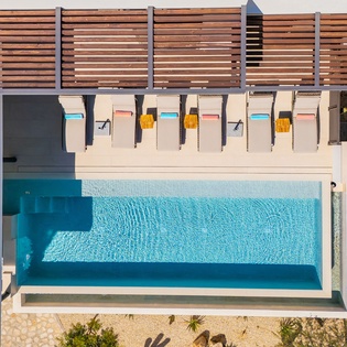 Aerial view of the property's swimming pool area with modern poolside loungers and wooden privacy screening.