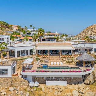 Stunning hillside property perched on dramatic rocky terrain with panoramic coastal views and neighboring luxury homes.