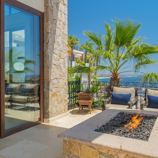 Relax by your private fire pit as ocean waves meet the horizon, tropical palms swaying overhead on this stunning terrace.