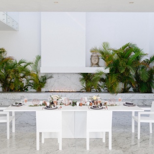 Your elegant dining space awaits with modern white furnishings and tropical palms creating a serene atmosphere.