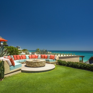 Stunning oceanfront terrace with curved seating overlooking turquoise waters and pristine beach.