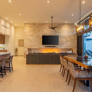 Relax in your elegant open-plan living space with stone fireplace, modern kitchen, and oceanview dining for unforgettable vacation moments.