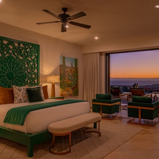 Unwind in your elegant bedroom with stunning sunset views through floor-to-ceiling windows, where emerald accents and luxurious furnishings create the perfect retreat.