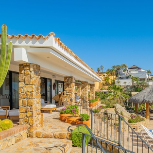 Stunning desert villa featuring stone columns, terracotta roofing, and vibrant cacti creating an authentic Mexican retreat atmosphere.