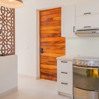 Your modern kitchen features sleek white cabinets, stainless steel appliances, and beautiful decorative wood accents that create a warm cooking space.