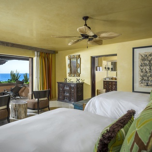 Unwind in your luxurious oceanfront bedroom where tropical breezes flow through open doors and stunning sea views create the perfect escape.