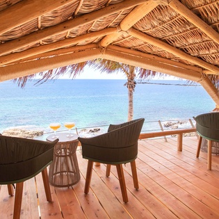 Sip morning coffee beneath a thatched palapa as turquoise waves lap the shore just steps from your private dining terrace.