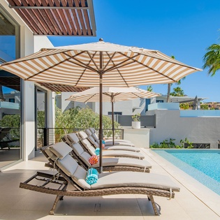 Bask in your private poolside paradise with plush loungers and tropical shade umbrellas under endless blue skies.