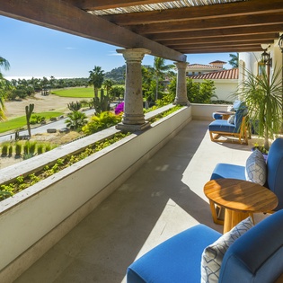 Relax on your private covered terrace with golf course views and comfortable blue seating.