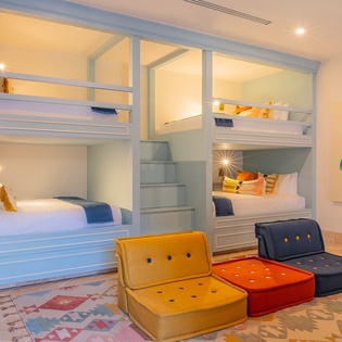 Your kids will love these cozy bunk beds with built-in reading lights, while colorful floor cushions create the perfect play space.