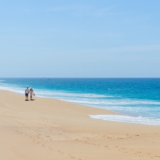 Pristine sandy beach stretches along crystal-clear turquoise waters, offering endless coastal beauty for peaceful oceanfront getaways.