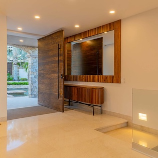 Polished floors, warm wood accents, and soft lighting welcome you into your vacation retreat, opening to lush tropical views beyond.