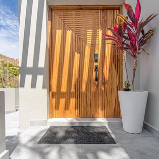 A stunning entrance showcases modern design with warm wood doors and desert mountain views welcoming your arrival.