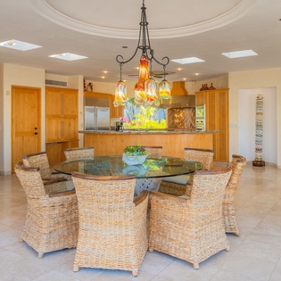 Gather around this stunning glass dining table where natural light streams through skylights, creating the perfect setting for your memorable meals together.