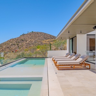 Modern desert retreat with infinity pool, luxury loungers, and stunning mountain backdrop perfect for serene outdoor relaxation.