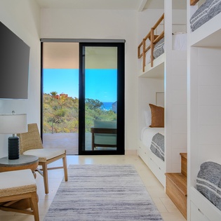 Your modern bedroom features custom bunk beds and stunning sea views through floor-to-ceiling windows.
