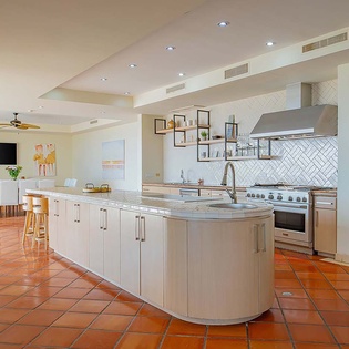 Step into your dream kitchen where warm terracotta tiles meet sleek modern design—a spacious island invites you to prepare meals while taking in the open flow to your dining area.