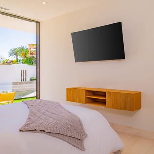 Unwind in your modern bedroom with crisp linens, sleek TV entertainment, and direct patio access to sunny outdoor seating.
