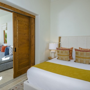 Drift into peaceful sleep in your elegant bedroom suite, featuring a plush bed with vibrant accents and seamless connection to your private living space.