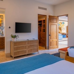 Your elegant twin bedroom features warm wood furnishings, vibrant blue accents, and modern amenities including a wall-mounted TV for your comfort.