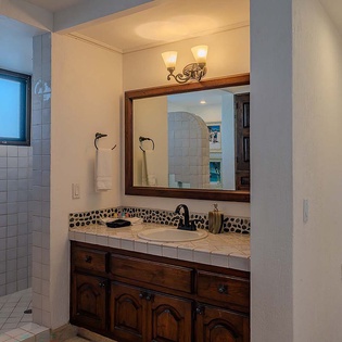 Refresh in your elegant bathroom with custom tile work, a spacious walk-in shower, and beautiful vanity—all bathed in natural light from seaside windows.
