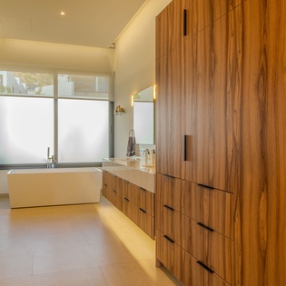 Step into your luxurious spa-like bathroom featuring rich walnut cabinetry and a stunning freestanding tub for ultimate relaxation.