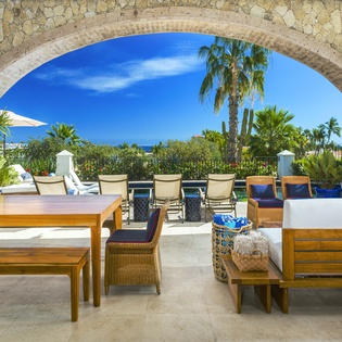 Relax in your private outdoor living space where elegant stone arches frame tropical views and comfortable seating invites endless moments of pure tranquility.