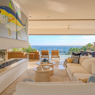 Relax in your stunning oceanfront living room where vibrant art meets endless sea views through floor-to-ceiling windows.