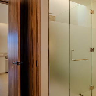 Indulge in your spacious glass-enclosed shower with gleaming fixtures and warm wood accents that create a spa-like sanctuary.